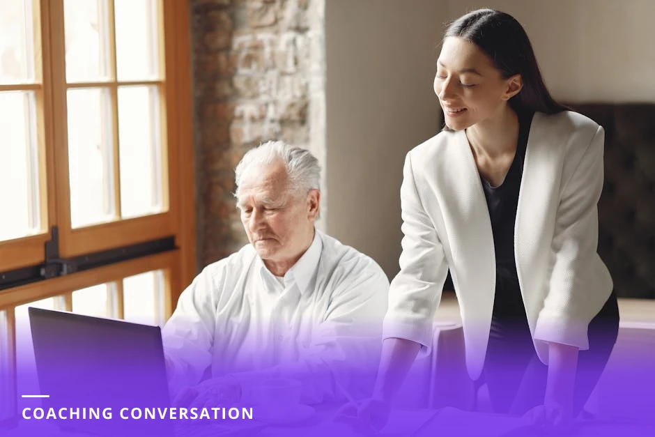Coach and client leaning over a notebook at a modern cafe table, engaged in a focused conversation with coffee and a phone on the table