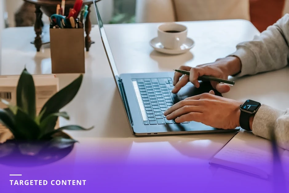 Professional at a bright modern Western desk typing on a laptop with a notepad and coffee beside them, natural window light and candid composition