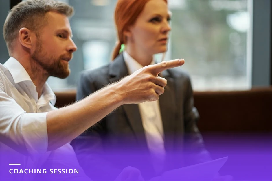 Career coach and client leaning over a laptop in a modern Western office; coach points at the screen showing a LinkedIn feed while they discuss strategy, candid natural light
