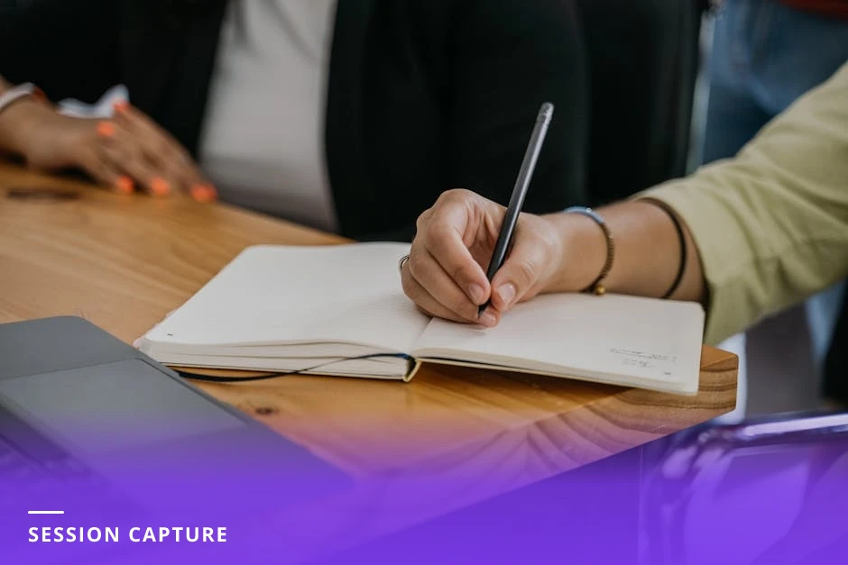 Coach alone at a desk in a modern Western office, writing a short session note beside an open laptop and coffee mug, warm natural light