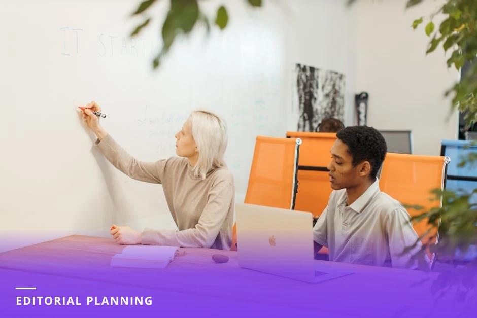 Diverse three-person team standing at a glass whiteboard placing sticky notes and mapping an editorial calendar in a modern workspace