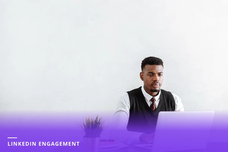 A young professional at a bright Scandinavian-style desk, focused on a laptop screen showing a LinkedIn profile, coffee mug and notebook beside the laptop, soft natural light and modern workspace.