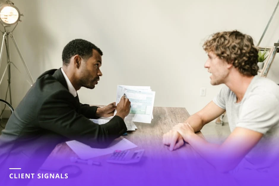 Diverse mentor and client seated in a bright cafe, leaning over a smartphone displaying a LinkedIn profile or comment thread, pointing and discussing potential clients.