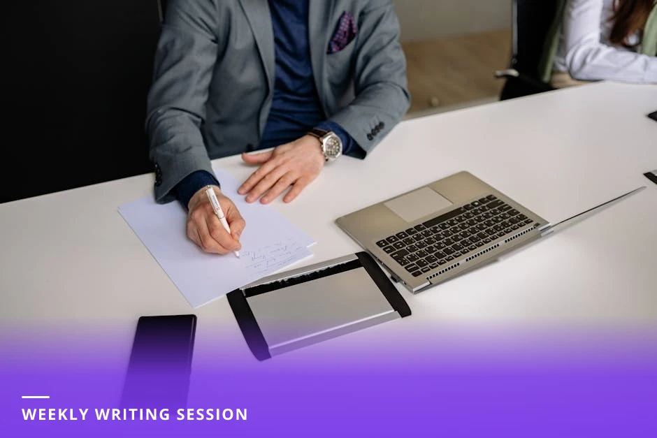 Coach focused at a bright Scandinavian-style office desk, typing on a laptop with notebook and timer visible, composing multiple posts