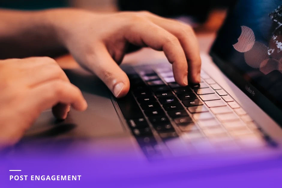 Close-up of hands typing on a laptop displaying a LinkedIn post with multiple comments and reactions, on a tidy modern Western workspace with a coffee cup