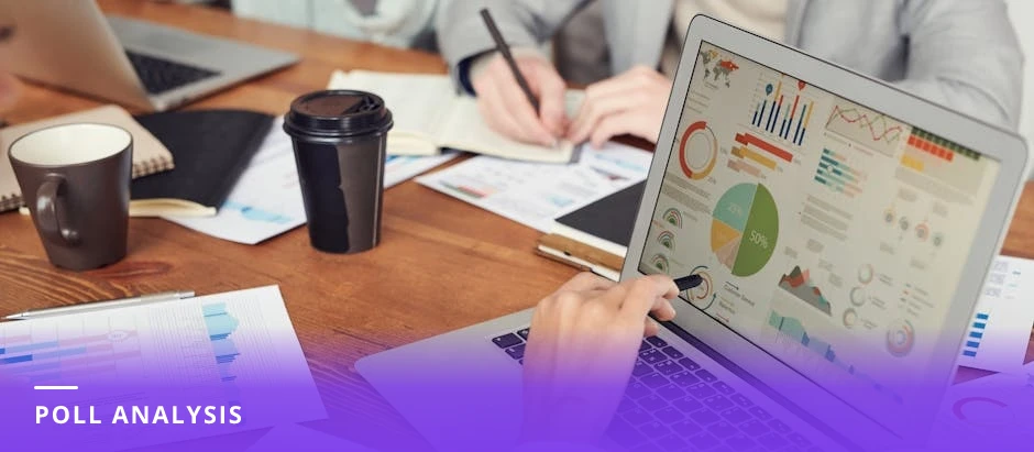 Career coach at a bright modern Western desk looking at a laptop screen showing poll results and charts, notebook, pen, and coffee on the desk, natural window light