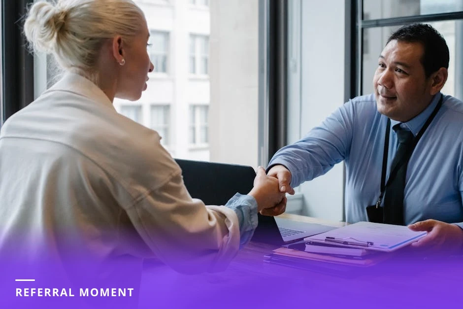 Coach and client shaking hands in a bright Scandinavian office, both smiling in business-casual clothes with plants and natural light in background