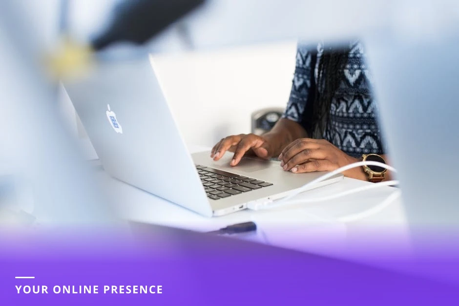 Professional woman typing on a laptop at a bright modern Western office desk with a notebook and coffee, creating content for social media.