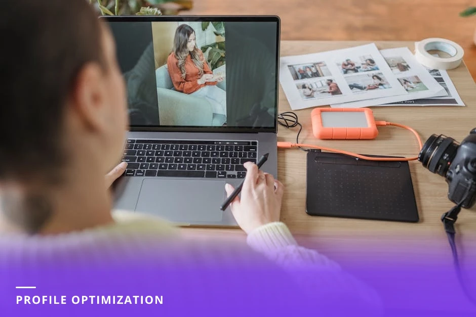 Professional woman editing her LinkedIn profile on a laptop in a bright modern Western office, over-the-shoulder candid view with natural light