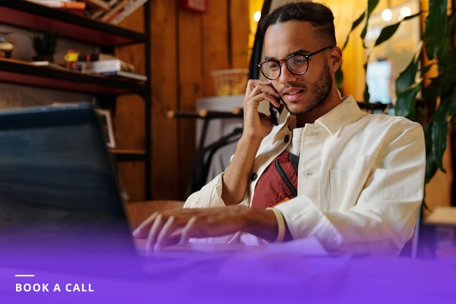 Person in a bright Scandinavian cafe typing on a laptop, screen visible with a calendar page and they are clicking to schedule a call.